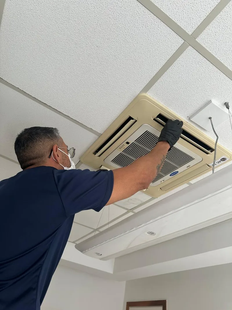 Técnico da Colder Climate fazendo a manutenção programada de um ar-condicionado cassete em teto comercial